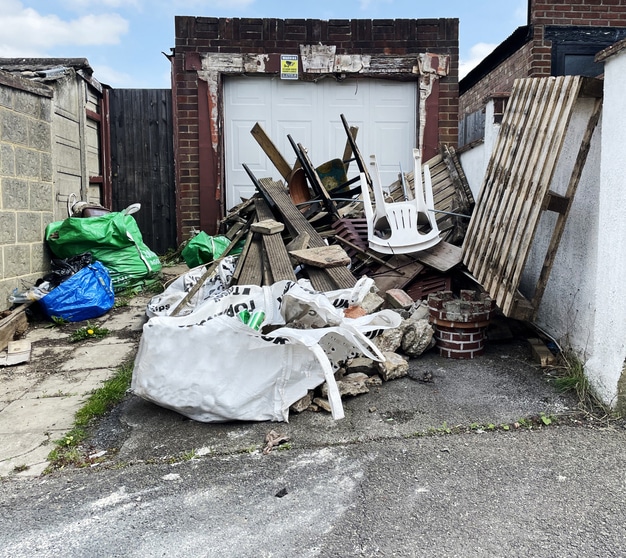 Allée de garage encombrée de déchets avant le passage d'un service de vide-maison à Liège